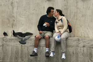 Couple kissing on ledge with pigeons